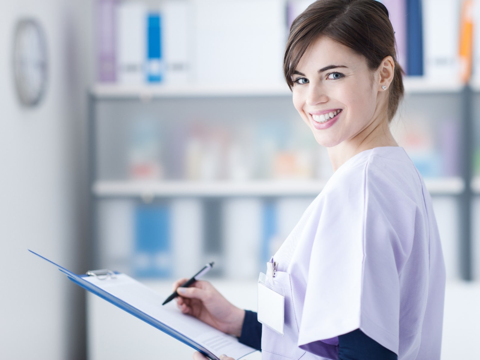 Nurse smiling at the camera with a clipboard in her hands