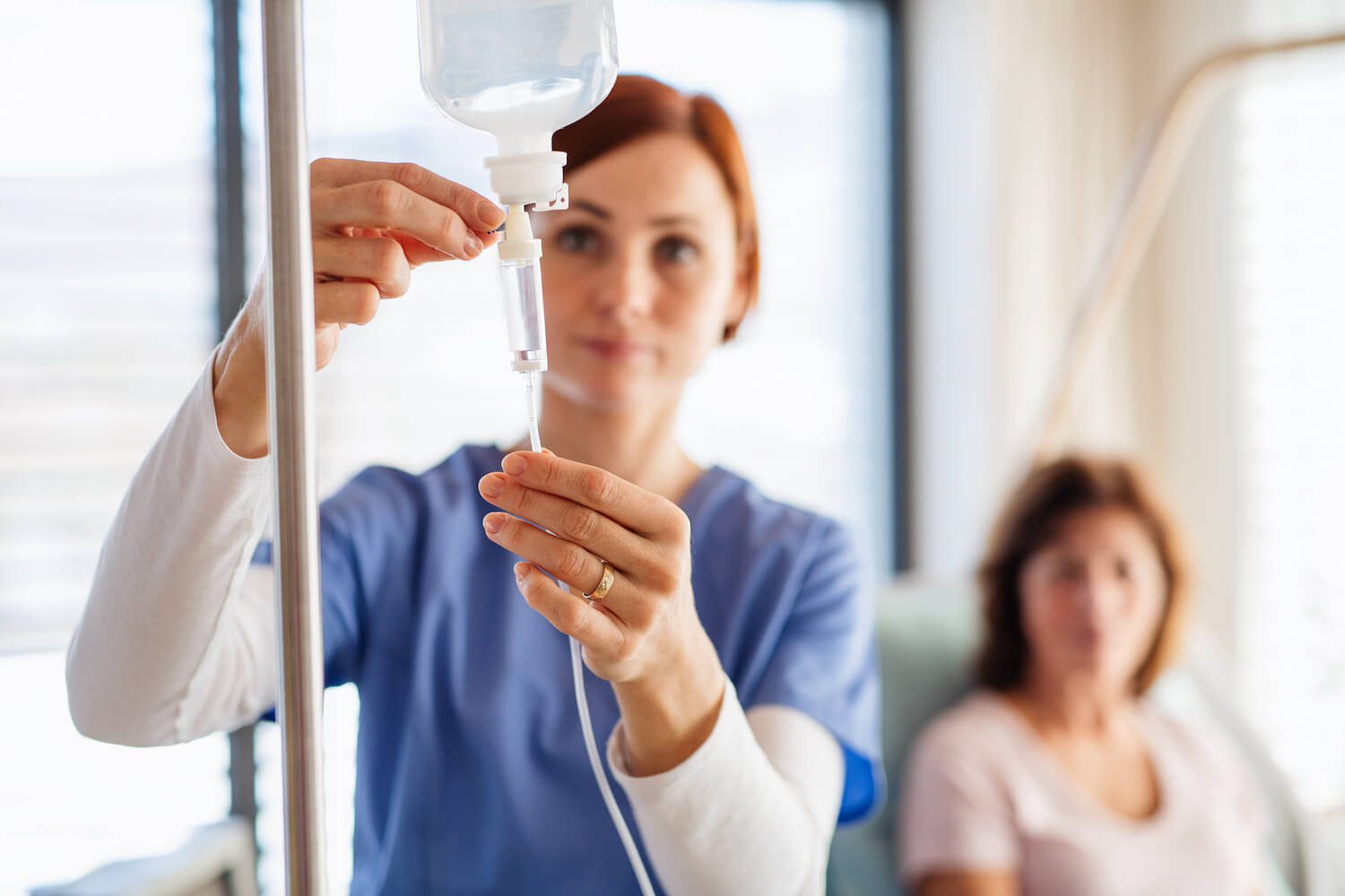 A healthcare professional is adjusting an IV bag with focused attention.