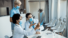 Healthcare professionals, wearing masks, are engaged in a discussion over a medical image in a modern office environment.